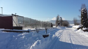 Un camino rural cubierto de nieve con una valla en un lado y un edificio en el otro.