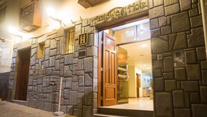 A stone facade with a wooden door and a sign indicating a hotel. - Antawasi Cusco (Cusco)