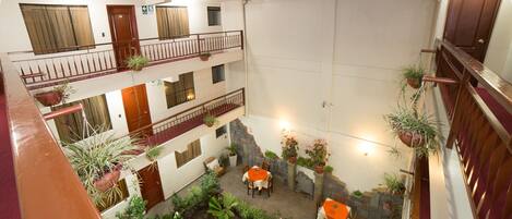 A multi-level courtyard with balconies, potted plants, and outdoor seating areas.