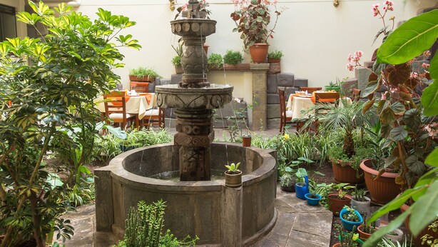 A courtyard with a stone fountain, potted plants, and outdoor seating. - Antawasi Cusco (Cusco)