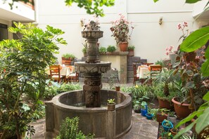 A courtyard with a stone fountain, potted plants, and outdoor seating. - Antawasi Cusco (Cusco)