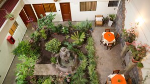 An indoor courtyard with a central fountain, surrounded by potted plants and a seating area with tables and chairs. - Antawasi Cusco (Cusco)