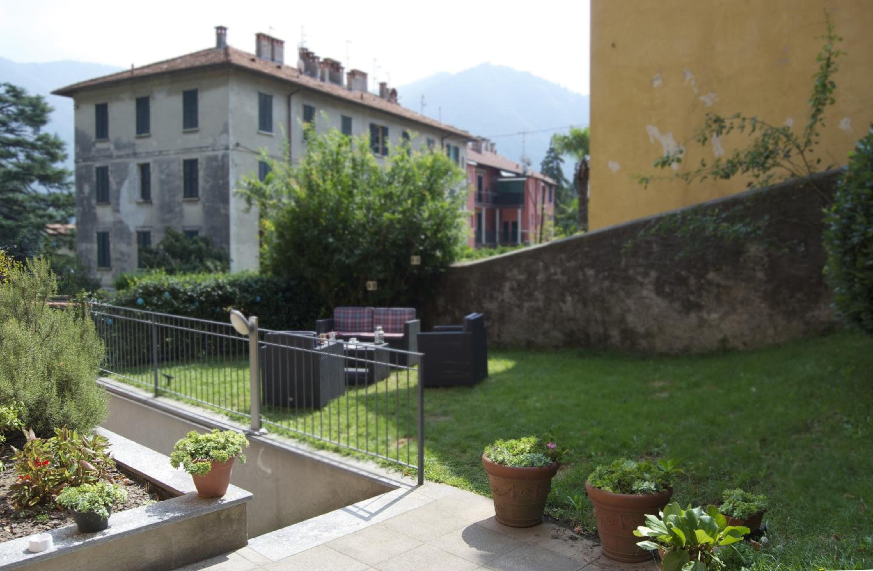 Une cour avec un petit espace aménagé pour s’asseoir, un mur en pierre et des plantes en pot.