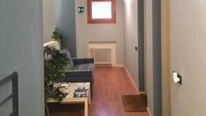 Un couloir étroit avec un radiateur, une fenêtre et une porte sur le côté droit.