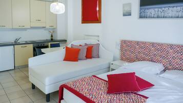 A modern hotel room with a kitchenette, a bed with patterned bedding, and a view of a natural landscape.