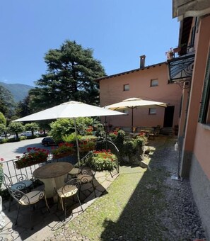 An outdoor patio with a table and chairs, surrounded by potted plants and a large umbrella. - Cernobbio Residence (Cernobbio)