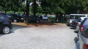 Un estacionamiento con varios coches y un autobús, rodeado de árboles.