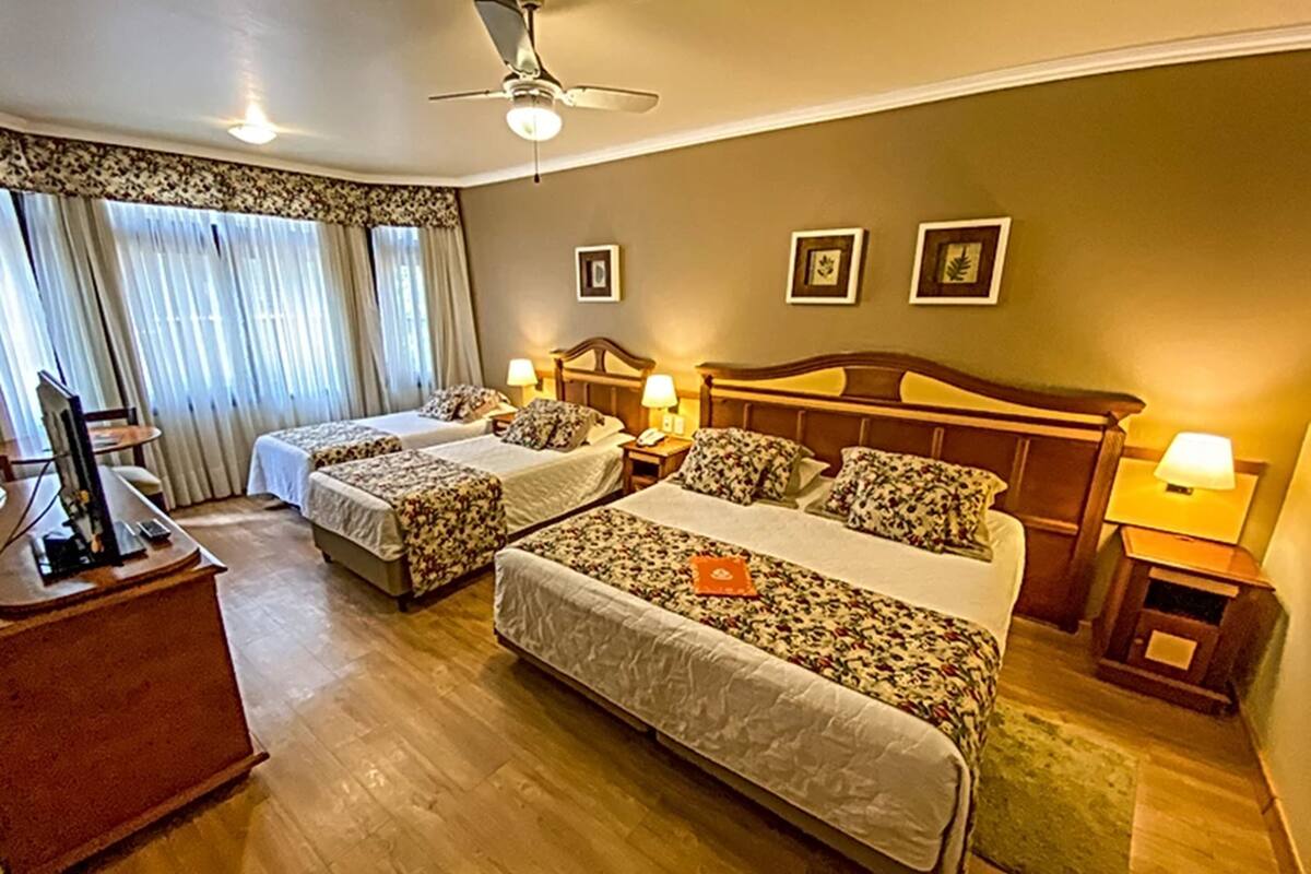 A hotel room with two beds, a desk, and a ceiling fan.