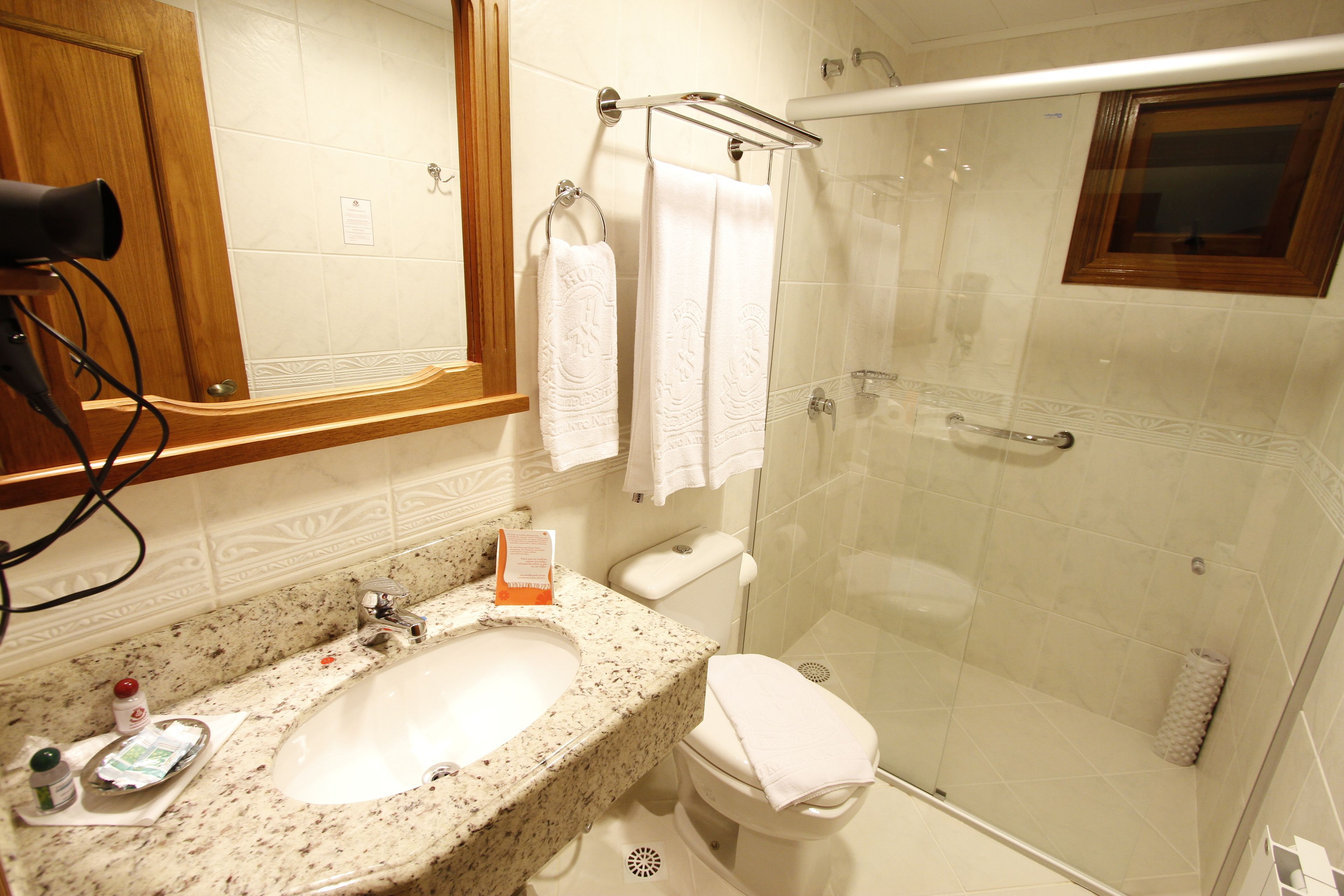 Un baño con lavamanos de granito, un espejo, un inodoro y una ducha con mampara de vidrio.