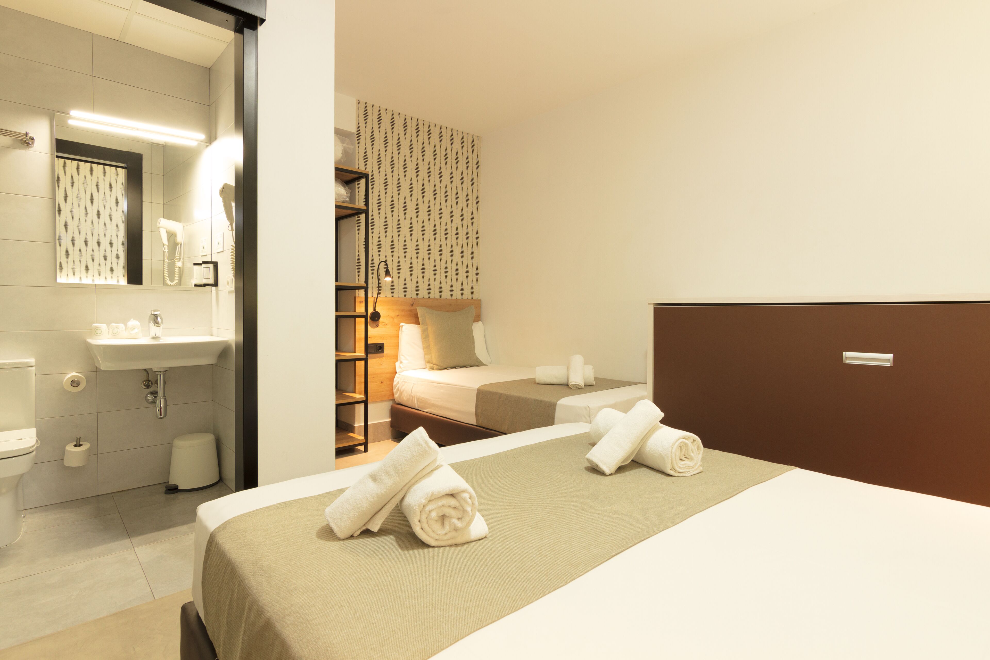 Una habitación de hotel con cama, baño con lavamanos y zona de ducha.