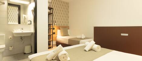 Una habitación de hotel con cama, baño con lavamanos y zona de ducha.