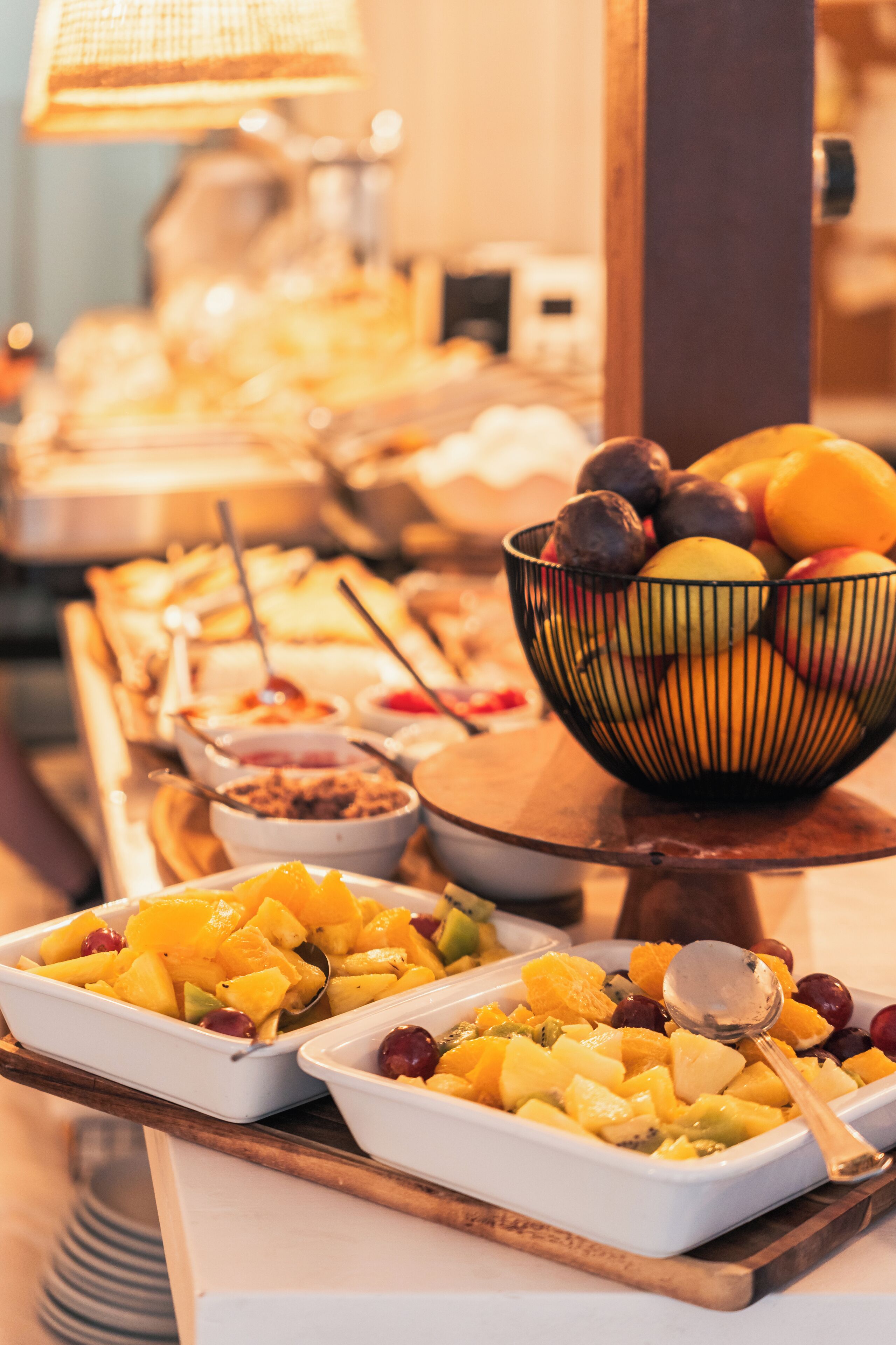 A buffet table with various food items and a fruit bowl.