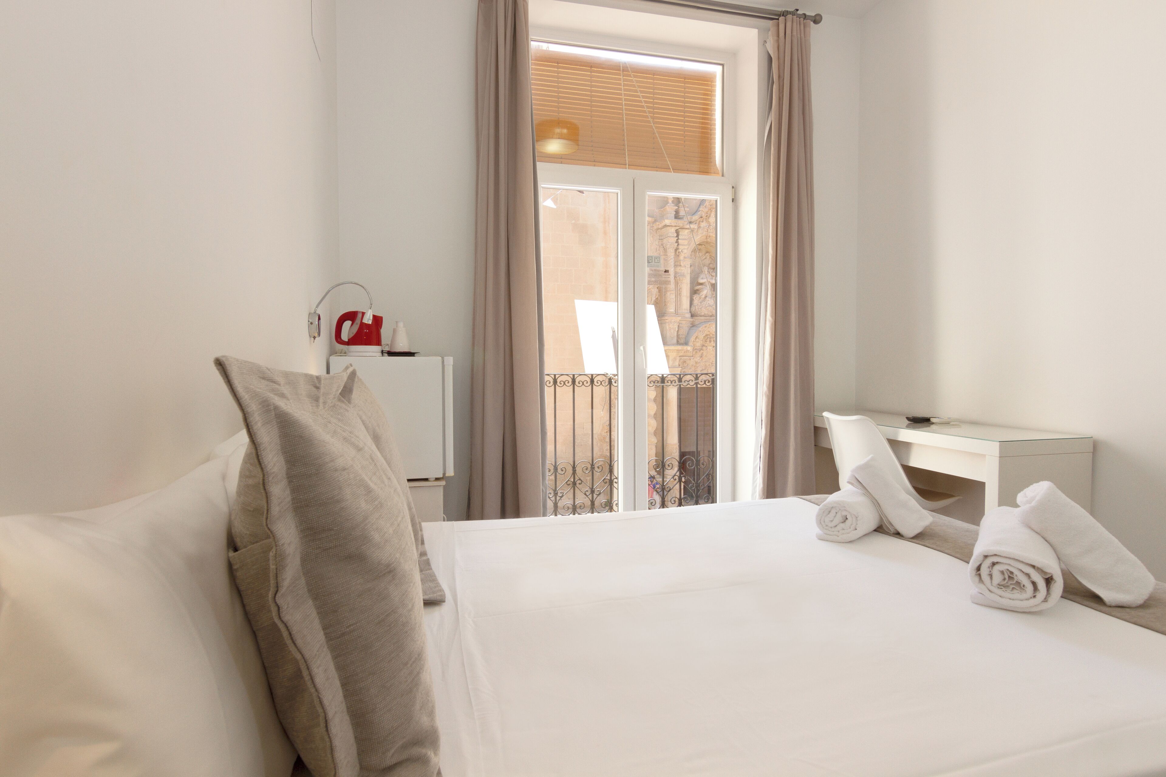 Ein Hotelzimmer mit einem Bett, einem Schreibtisch und einem Vorhangfenster.