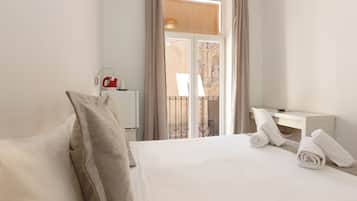 Habitación de hotel con cama, escritorio y ventana con cortinas.