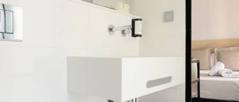 A modern bathroom with a white sink, a mirror, a hairdryer, and a toilet.