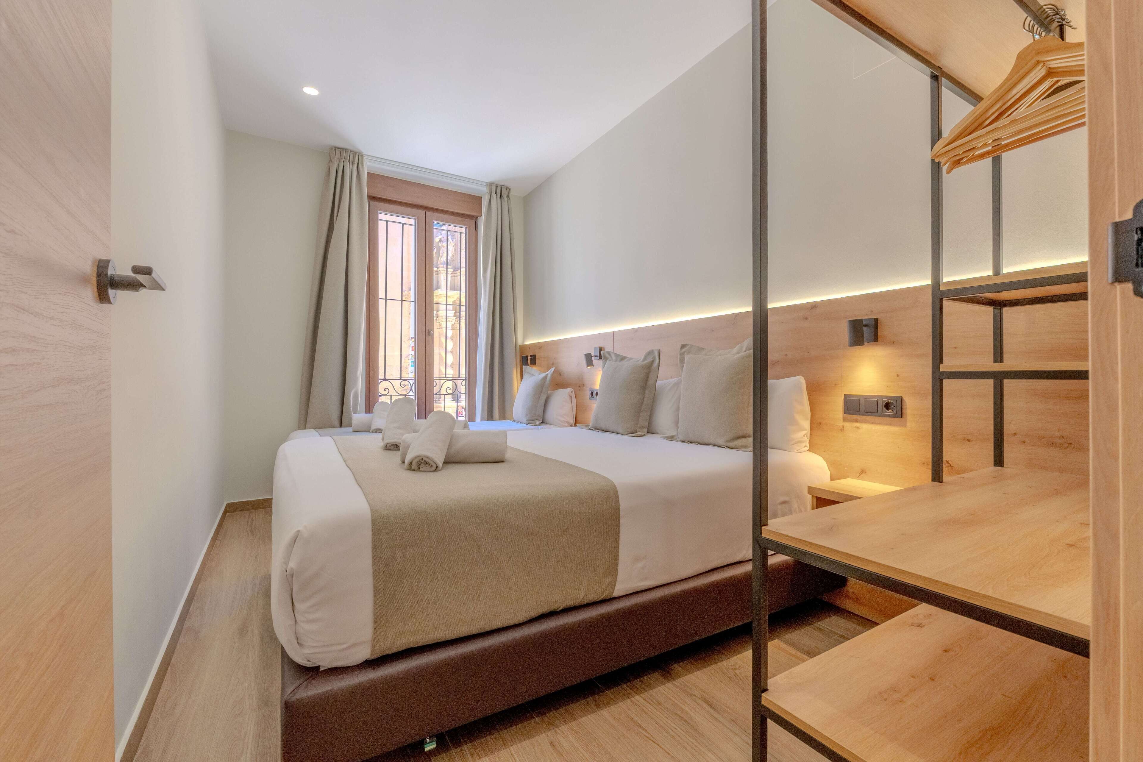 A modern hotel room with a large bed, a wooden desk, and a window with curtains.