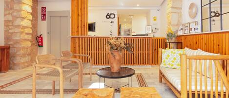 Un vestíbulo con mostrador de recepción, muebles de madera, pared de piedra y extintor.