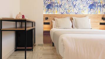 A hotel room with a wooden headboard, a bed with white bedding, a small table with a decorative item, and a wall with a blue and yellow abstract pattern.