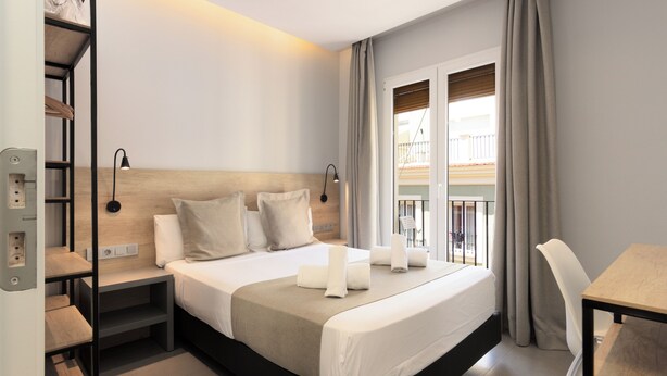 A modern hotel room with a large bed, bedside tables, a desk, and a view of the outside balcony. - Hotel La Milagrosa (Alicante)