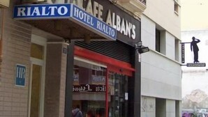 A hotel named "Hotel Rialto" with a red awning and a sign indicating amenities like a restaurant, parking, and a phone. - Hotel Rialto (Alicante)