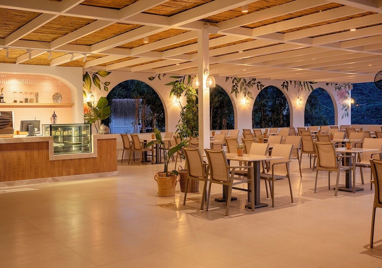 A restaurant with a wooden ceiling, tables, chairs, and a counter with a display case.