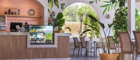 Un área de comedor al aire libre moderna con mostrador de madera, asientos y plantas en macetas.