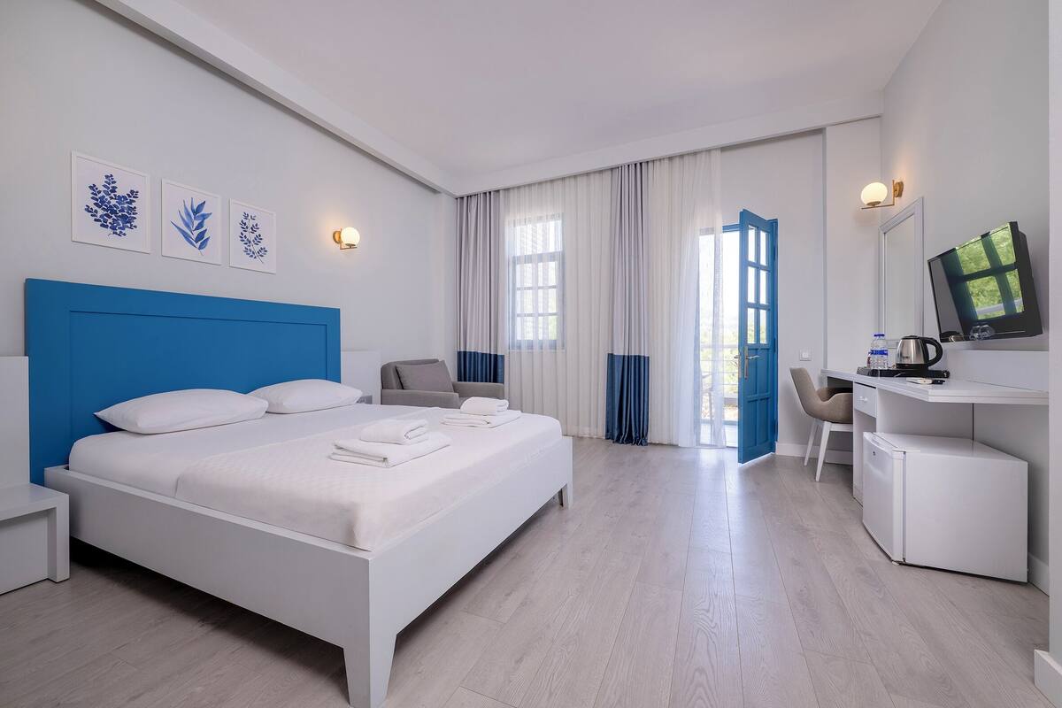 A modern hotel room with a large bed, a desk, a chair, and a television.