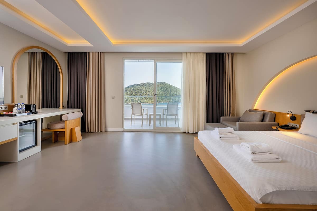 A modern hotel room with a bed, desk, and balcony.