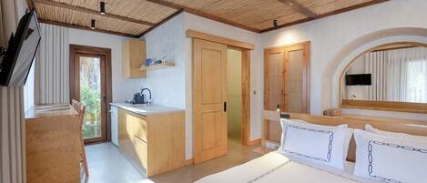 A bedroom with a large bed, wooden ceiling, and a view of the outdoors.