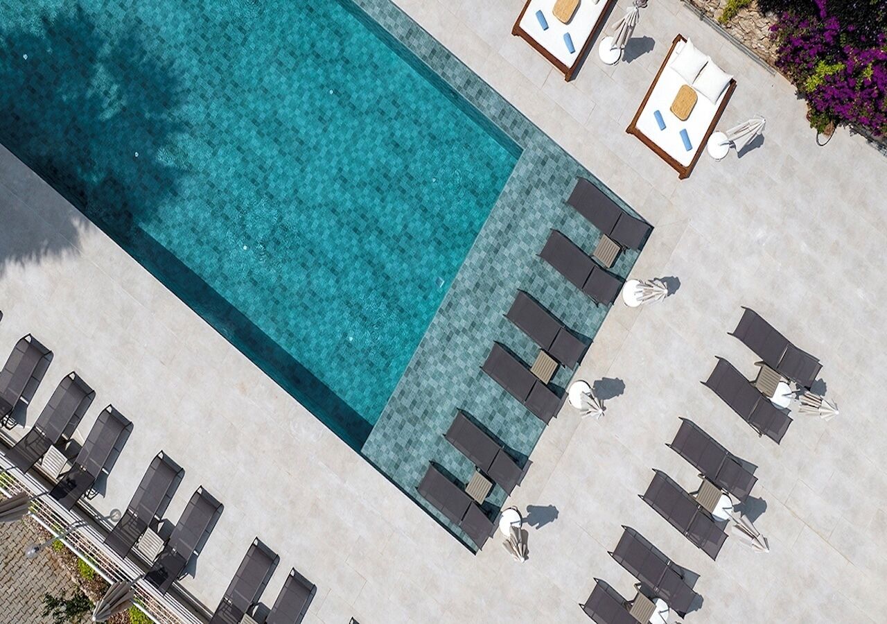 An aerial view of a swimming pool with lounge chairs and sunbeds arranged around it.