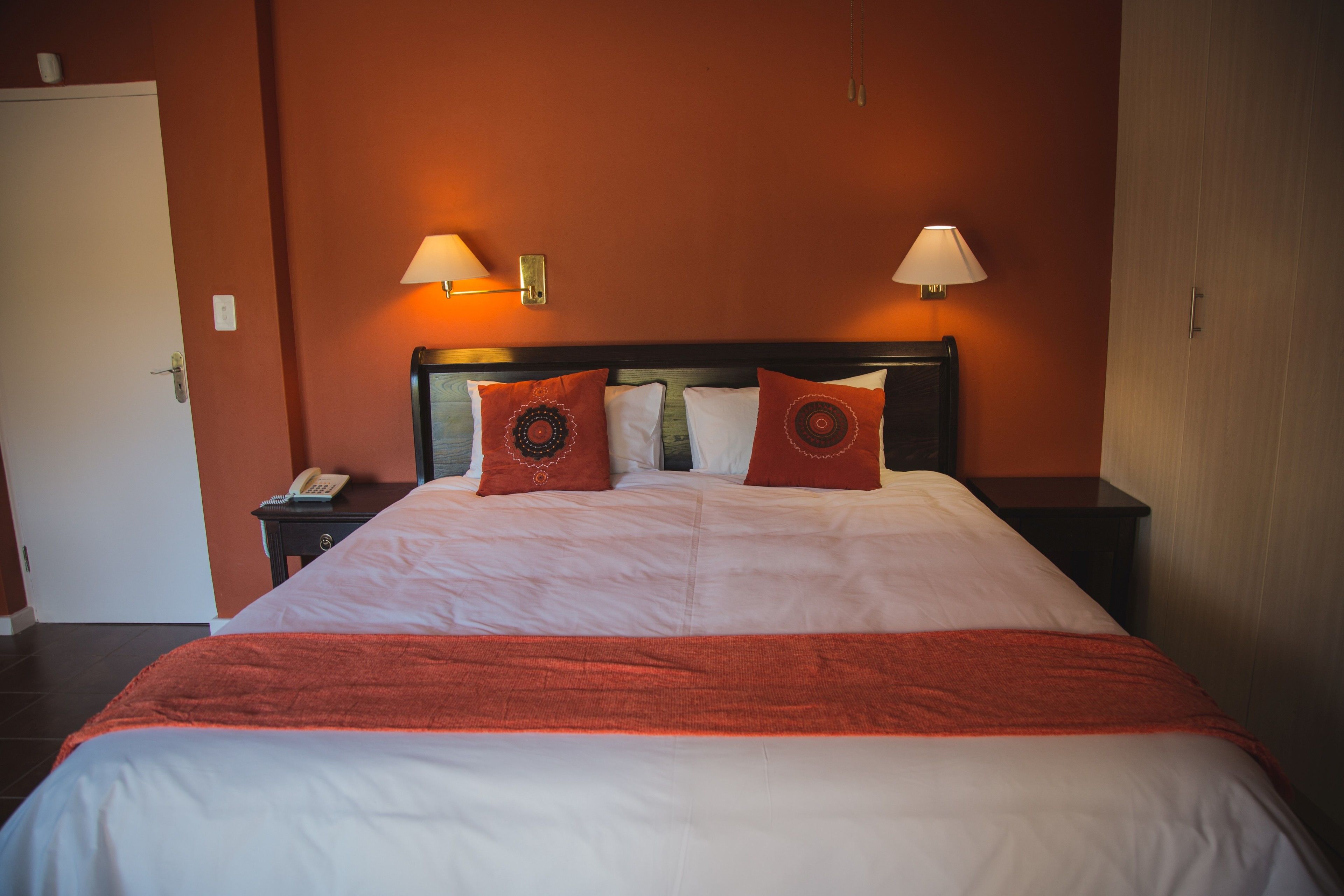 Una habitación de hotel con una cama grande, dos lámparas de noche y un teléfono en la mesita de noche.