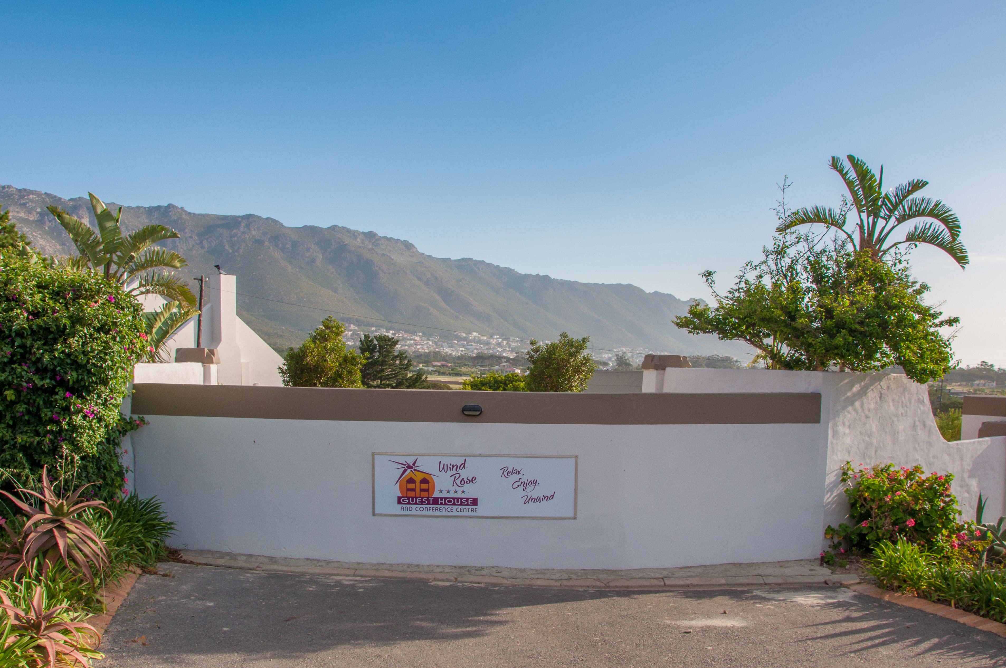 A guest house with a mountain view, a sign indicating it is a guest house and conference center, and a well-maintained garden.