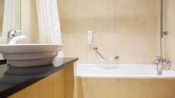 A bathroom with a sink, mirror, shower, and a towel rack.