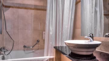 Een badkamer met een bad, een wastafel en een douche.