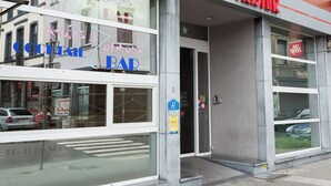 A hotel with a red sign, large windows, and a visible storefront with a bar. - Tristar (La Louviere)