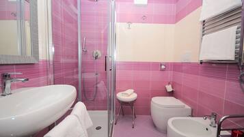 Un baño con ducha envuelta en vidrio, lavabo, bidé e inodoro.