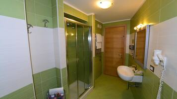 A bathroom with a shower, toilet, sink, and a wooden door.