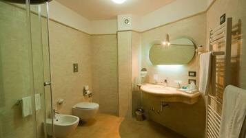 Une salle de bain avec une douche à parois de verre, des toilettes, un bidet, un lavabo avec un miroir et un porte-serviettes.
