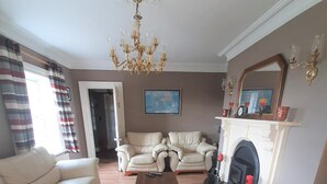 Una sala de estar con sofá, dos sillones, una mesa de centro, chimenea y candelabro.