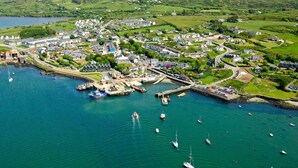 Vista aérea de un pueblo costero con un puerto deportivo, casas y barcos.