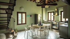 Una cuina àmplia amb taula i caires de fusta, forn integrat i una finestra gran que deixa entrar molta llum natural.