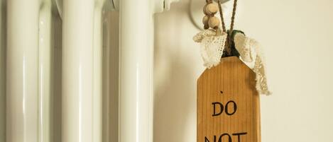 A radiator with a wooden tag that reads "DO NOT DISTURB".