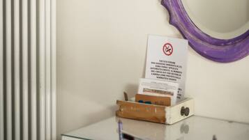 Ein Zimmer mit Heizkörper, Spiegel mit violetter Rahmen und Tisch mit einem Schild.