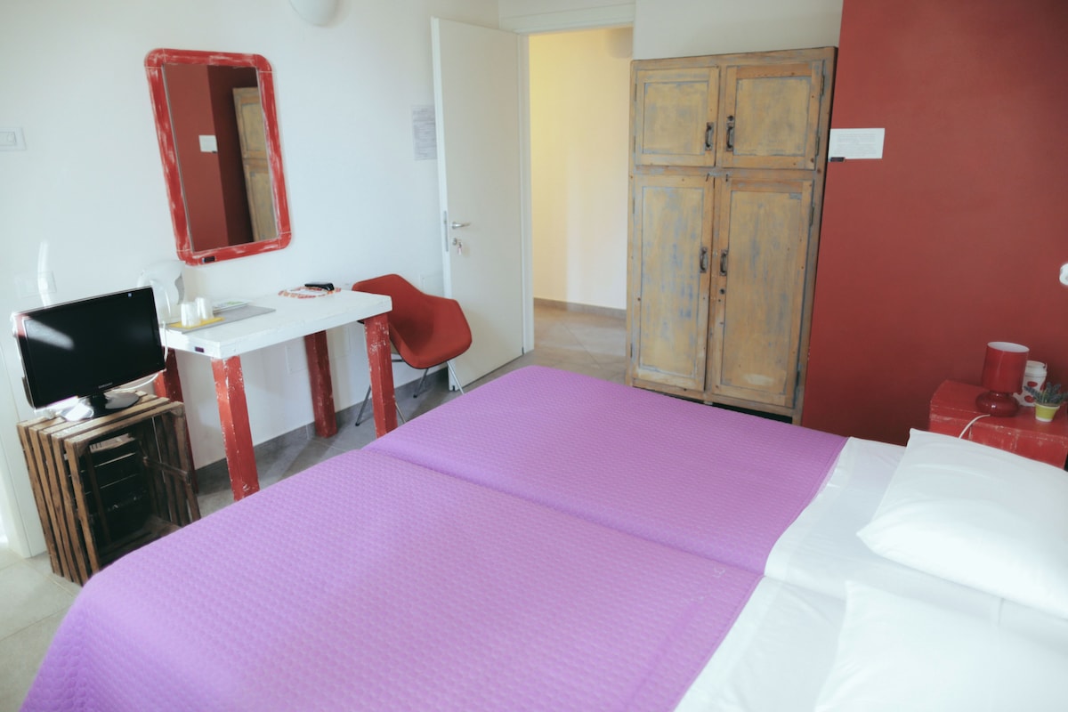 A room with a bed, a desk with a chair, a television, and a wardrobe.