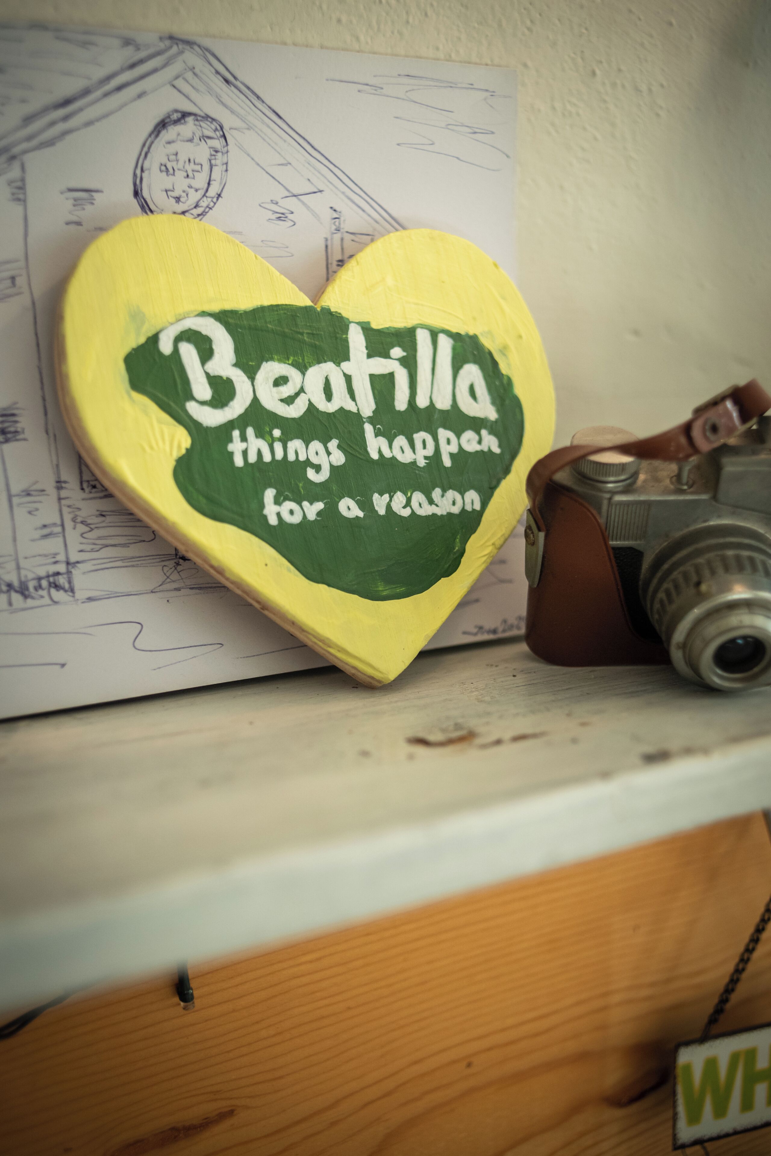 Una señal en forma de corazón con texto, una cámara y un trozo de papel con dibujos.