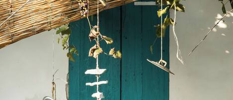 A rustic kitchen with a hanging grapevine, a teal door, and a white cabinet with a plant.