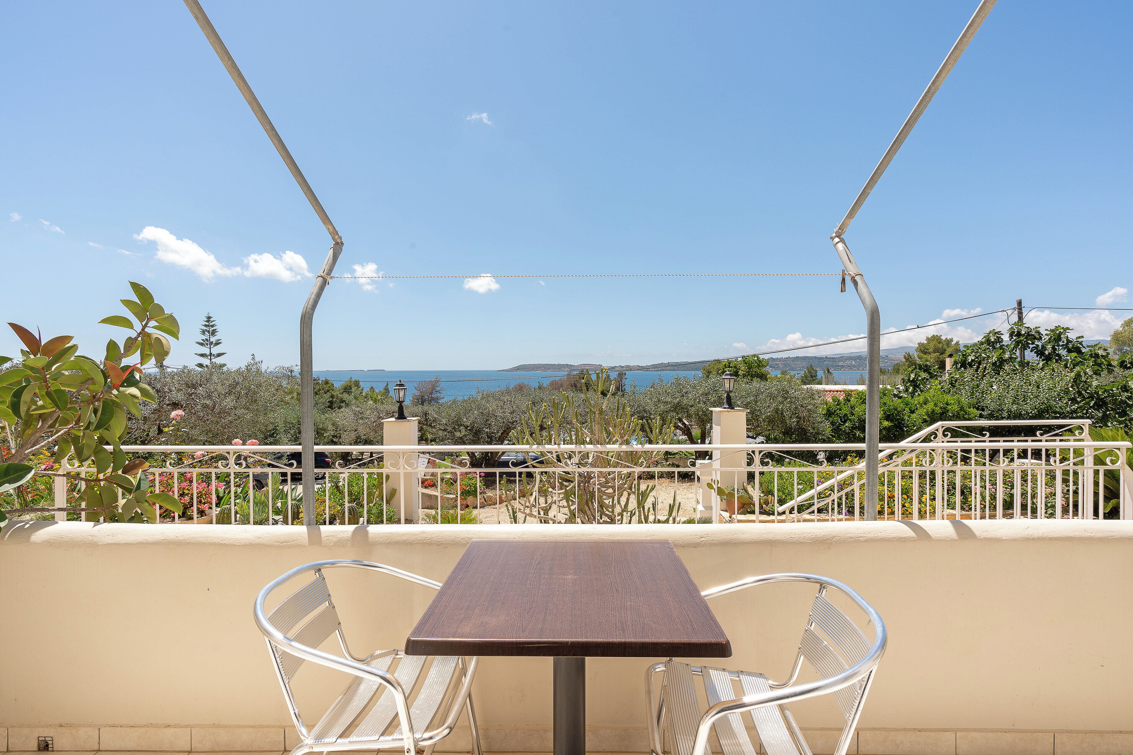 Ein Balkon mit Tisch und Stühlen, mit Blick auf einen Garten und eine entfernte Landschaft.