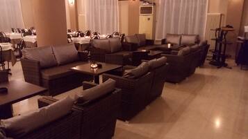 A spacious lounge area with multiple seating options including sofas and chairs, arranged around tables.