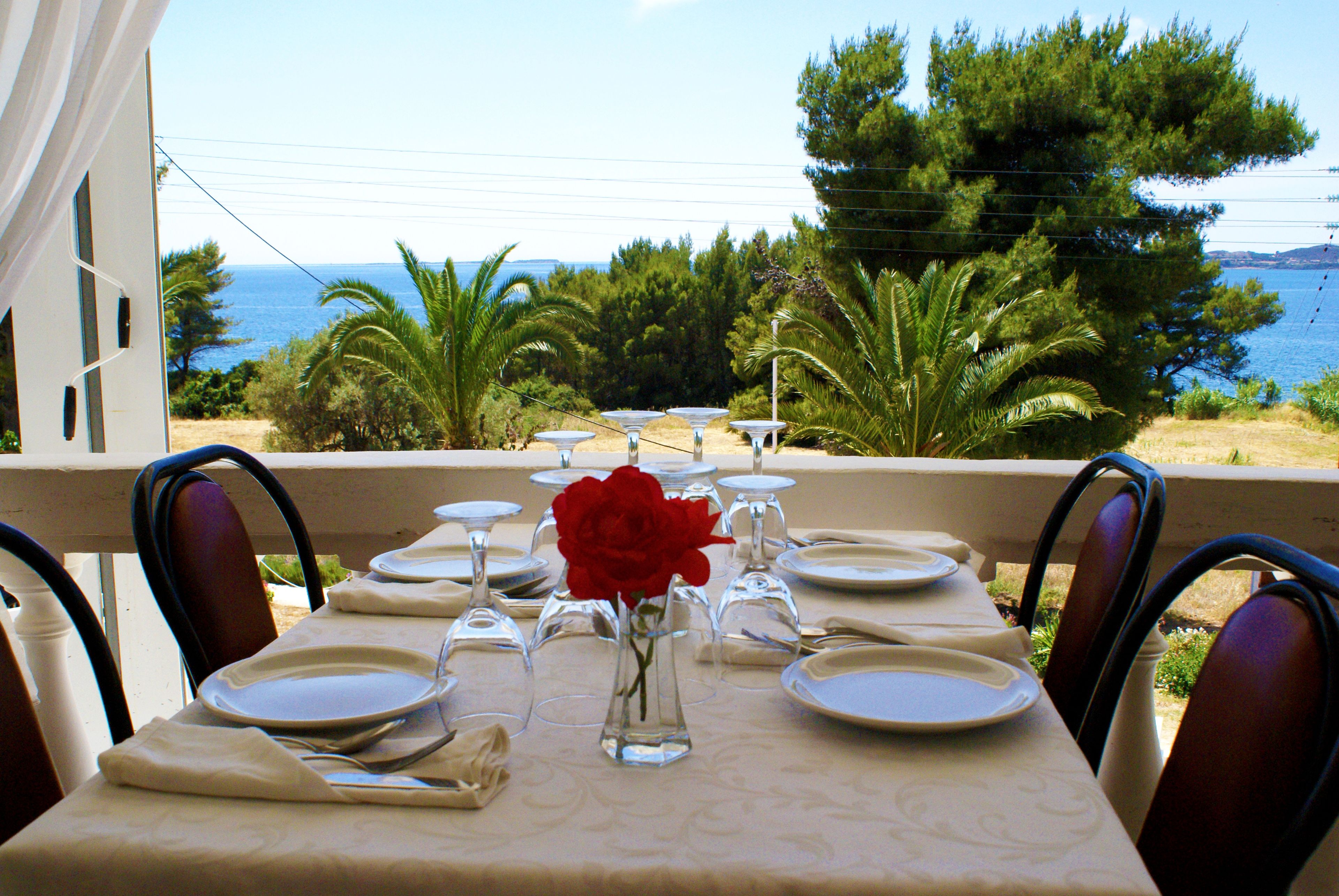 Une table dressée pour le dîner, avec vue sur la mer et les arbres.