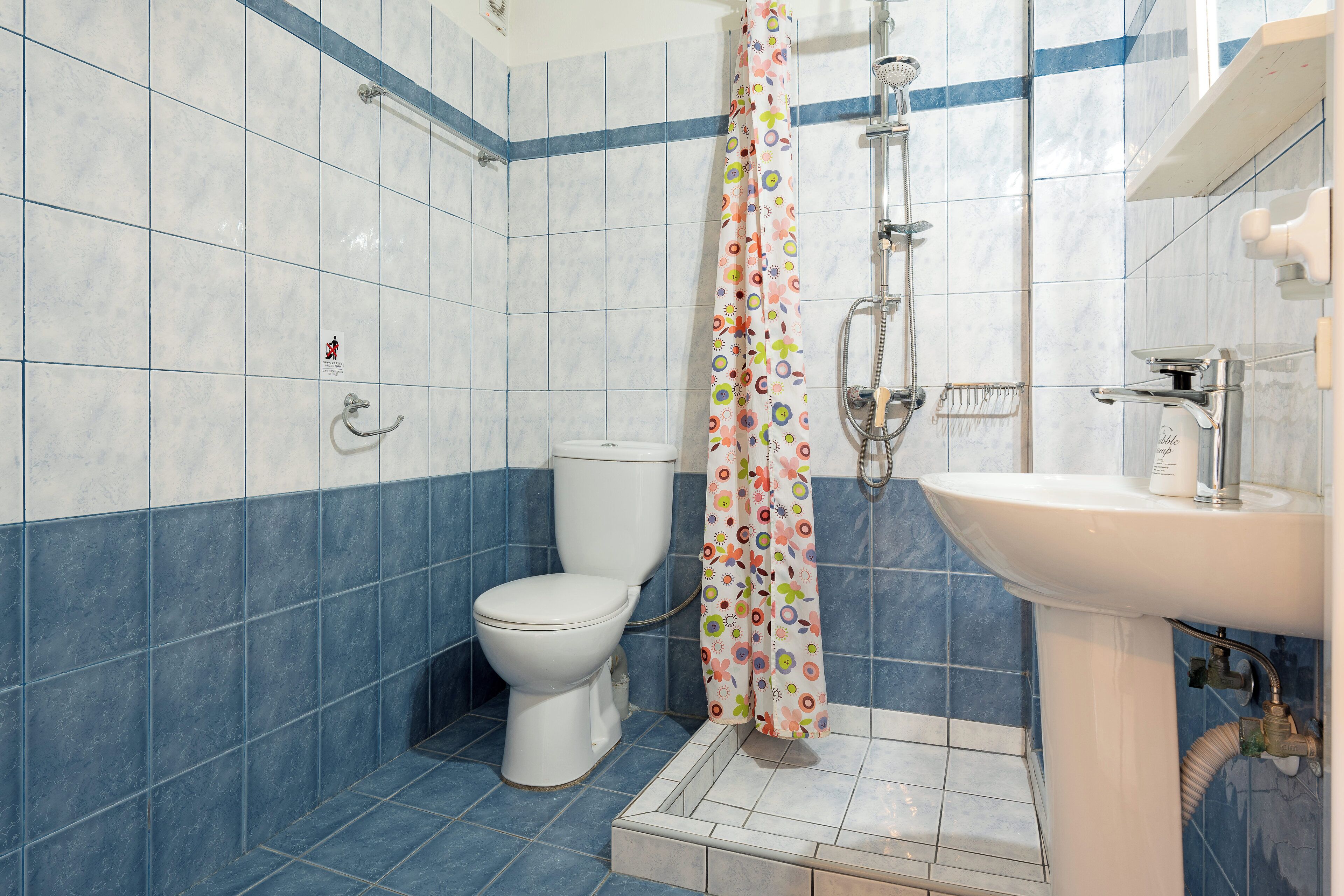 A bathroom with a toilet, shower, and sink.